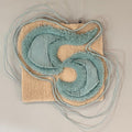 Textile art piece with swirling pattern on a neutral background